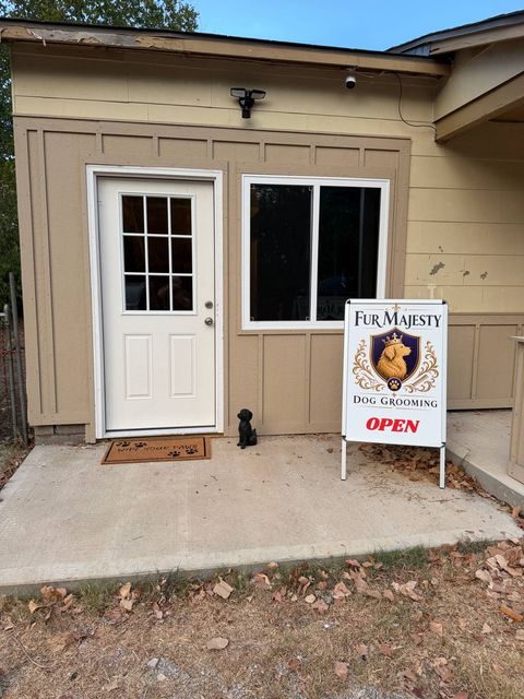 The Fur Majesty Dog Grooming entrance — a white door with a Wipe Your Paws mat and our Open sign out front